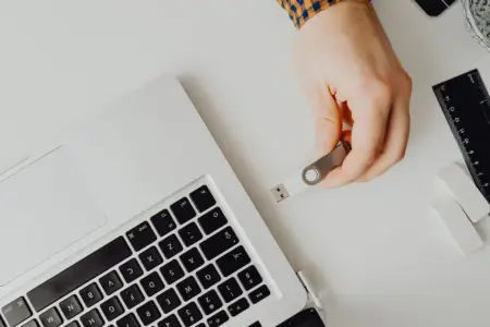 Hand inserting bootable USB drive into laptop for Windows 11 clean installation